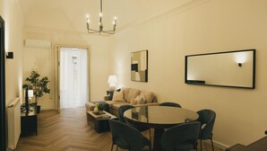 Una sala de estar moderna con una mesa de comedor redonda, dos sillones, un sofá, una lámpara y una planta en maceta.