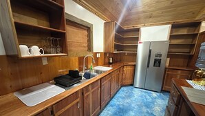 Una cocina compacta con armarios de madera, un lavamanos de acero inoxidable y un refrigerador integrado.