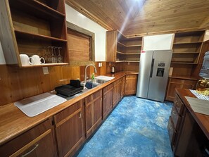 Una cocina compacta con armarios de madera, un lavamanos de acero inoxidable y un refrigerador integrado.