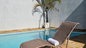 Ein Korbsessel mit Handtuch, platziert am Pool mit Fliesenböden.