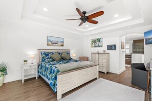 Une chambre à coucher avec un lit en bois, un ventilateur de plafond, une table de chevet avec une lampe et une grande fenêtre.