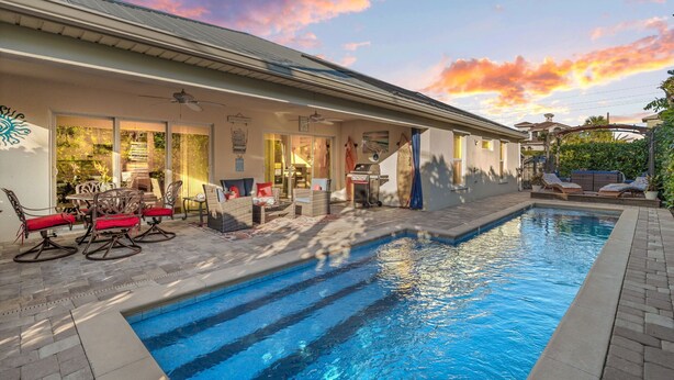 Un espace aménagé au bord de la piscine, avec une terrasse, des sièges d’extérieur et une vue sur le ciel.
