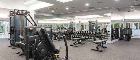 A modern gym with various exercise equipment, including weight machines and free weights.