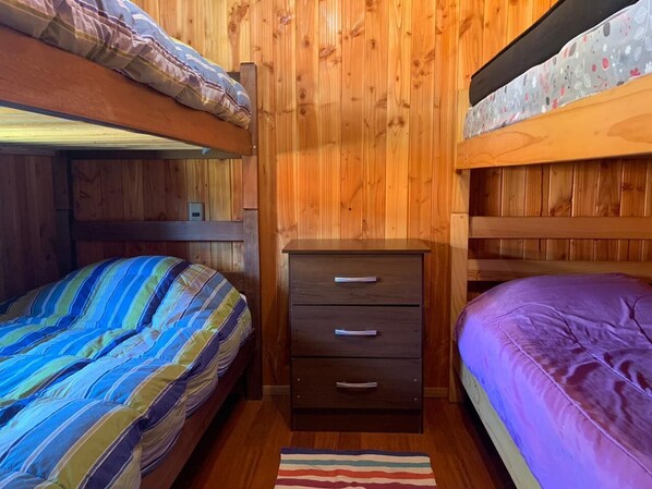 A bunk bed room with striped bedding, a wooden dresser, and a wooden wall. - Cozy cabin minutes from downtown Pucón (Pucon)