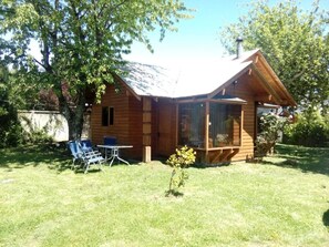A wooden cabin with a covered porch, a small garden, and a table with chairs. - Cozy cabin minutes from downtown Pucón (Pucon)