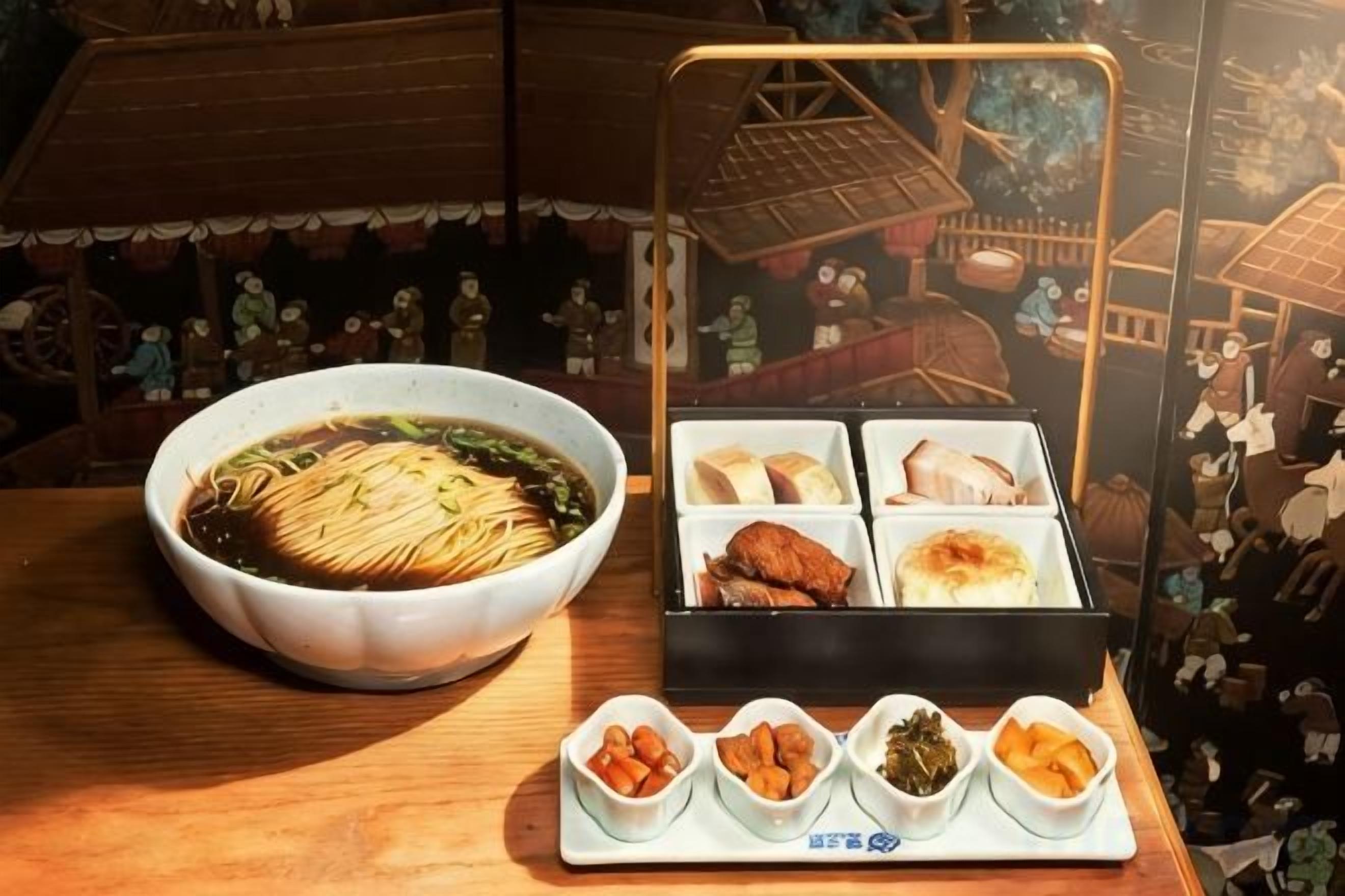 Una presentación tradicional de comida japonesa con un tazón de sopa, una bandeja de carne y pequeños platos de verduras encurtidas.