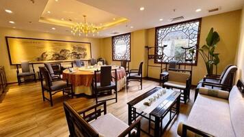 Uma sala de jantar tradicional com móveis de madeira, um candelabro e uma grande janela com vista.