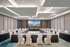 Un salón de conferencias con una larga mesa, sillas y vistas a la ciudad.
