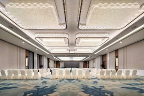 A conference room with a patterned carpet, rows of white chairs, and a high ceiling with recessed lighting. - SCHOLARS HOTEL·SELECT Collection Hotel (Suzhou Shilu Sanxiang Road Subway Station) (Suzhou)
