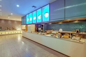 A modern restaurant with a long counter, blue-tiled backsplash, and illuminated menu boards. - SCHOLARS HOTEL·SELECT Collection Hotel (Suzhou Shilu Sanxiang Road Subway Station) (Suzhou)