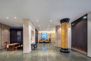 A hotel lobby with a reception desk, seating area, and a large pillar. - SCHOLARS HOTEL·SELECT Collection Hotel (Suzhou Shilu Sanxiang Road Subway Station) (Suzhou)