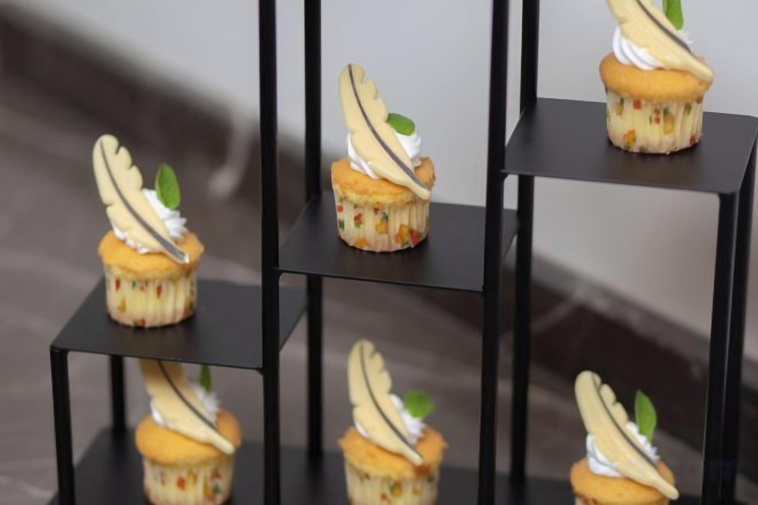 Una serie de cupcakes sobre pedestales negros cuadrados.