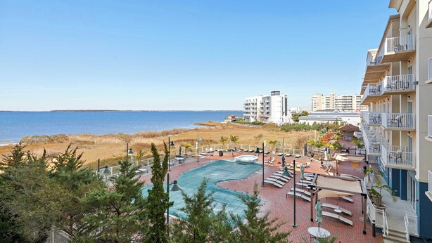 Een resort met een zwembad, terras buiten en uitzicht op het strand en de oceaan.