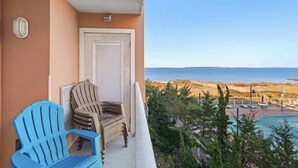 Een balkon met twee stoelen, een deur en uitzicht op het strand en de oceaan.
