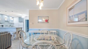 Una cocina moderna con gabinetes blancos, una mesa de comedor con sillas blancas y una lámpara colgante.