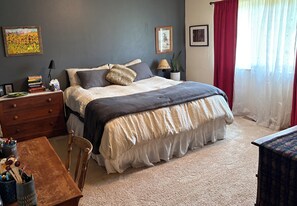 Un dormitorio ordenado con cama, mesita de noche, cómoda y silla.