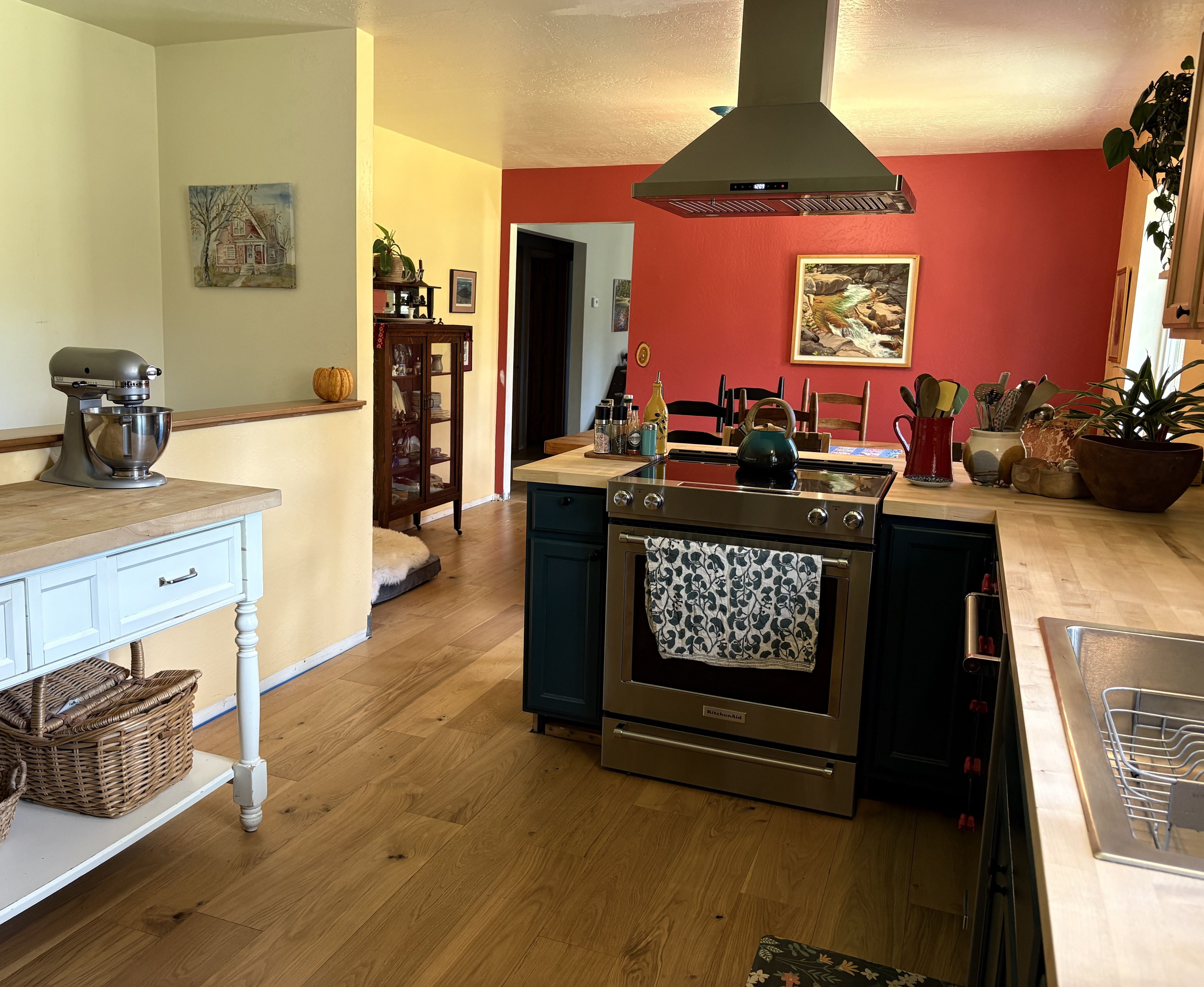 Una cocina con horno integrado, una batidora y un comedor con sillas y mesa.