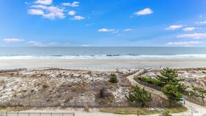 Blick auf einen Strand mit Sandfläche und Holzzaun.