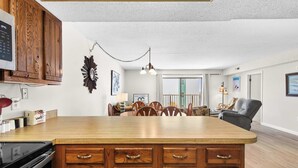 A spacious kitchen with a large island, wooden cabinets, and a dining area with chairs and a table. - Angelfish 207 (Ocean City)