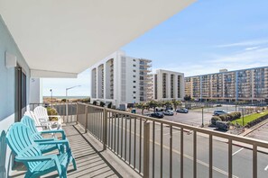 A balcony with two chairs, a view of a parking lot, and high-rise buildings in the background. - Angelfish 207 (Ocean City)