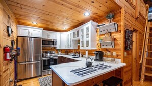 A modern kitchen with wooden walls, stainless steel appliances, and a central island.