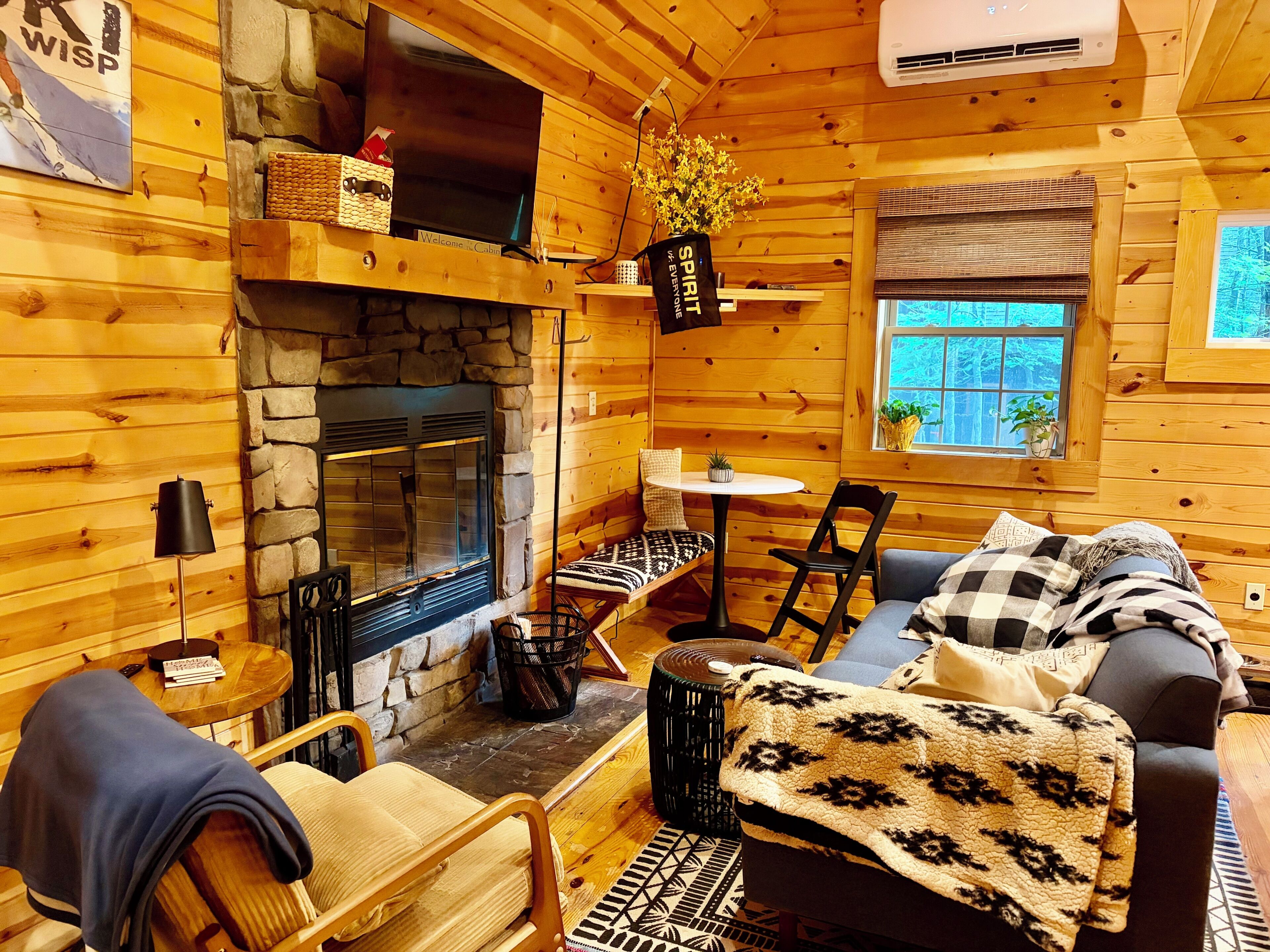 L’intérieur d’un chalet accueillant, avec une cheminée en pierre, des murs en bois, un canapé et une petite table.