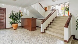 A spacious lobby with a staircase, a reception desk, and a large potted plant. - Your home with Comfort, Security and BBQ in El Poblado, Medellin! Super location (Medellín)
