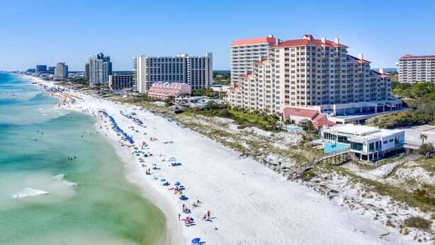 A beachfront hotel with multiple buildings, a sandy beach, and a clear blue sky. - 1BR oceanview studio with private balcony (Miramar Beach)