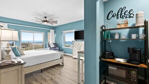 A bedroom with a bed, a desk, a coffee bar, a TV, and a view of the ocean. - 1BR oceanview studio with private balcony (Miramar Beach)
