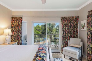 A hotel room with a bed, a chair, a table, a lamp, and a view of the outdoors through a sliding door. - Studio with Preserve Views Pools and Tennis (Miramar Beach)