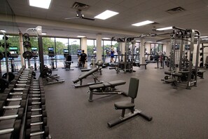 Ein Fitnessstudio mit unterschiedlichen Trainingsgeräten, großen Fenstern und Blick ins Freie.