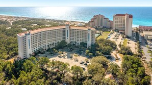 Un hotel gran amb diverses plantes, un aparcament i vista a l'oceà.