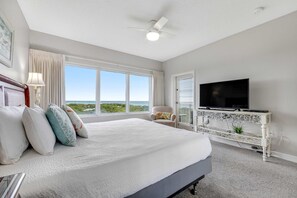 Un dormitorio con una cama grande, televisión y vista al océano.