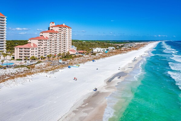 A beachfront hotel with multiple floors, a pool, and a beach view. - 1BR condo steps to beach, pools, hot tub (Miramar Beach)