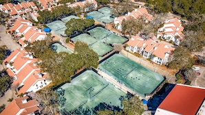 An aerial view of a residential area with multiple tennis courts surrounded by houses with red roofs. - 1BR condo steps to beach, pools, hot tub (Miramar Beach)