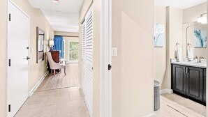 A hallway leading to a bathroom with a sink, mirror, and towel rack. - 1BR condo steps to beach, pools, hot tub (Miramar Beach)