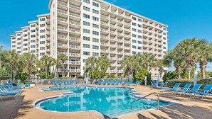 Un hotel con piscina, lettini e palme.