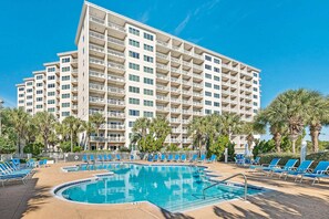 Ein Hotel mit Swimmingpool, Liegestühlen und Palmen.