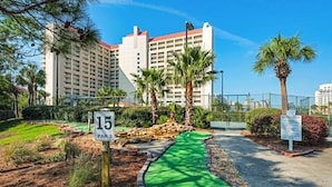 Un campo da golf con una zona putting verde, un cartello che indica il buco 15 e un edificio sullo sfondo.
