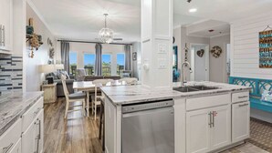 Cocina moderna con lavavajillas, comedor con mesa y sillas, y vistas al exterior.