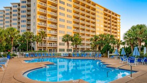 Um hotel com piscina, várias varandas e palmeiras.