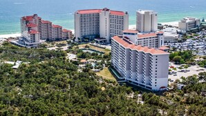 A coastal hotel complex with multiple high-rise buildings, a parking area, and a view of the ocean. - Exclusive Studio: Balcony, Pool, Beach Access (Miramar Beach)