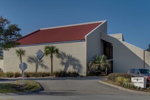 A building with a red roof, palm trees, and a sign for the Topps Club Fitness Center. - 3BR Gulf view condo with beach access (Miramar Beach)