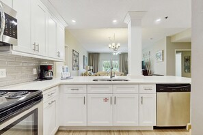 A modern kitchen with white cabinetry, a stainless steel range, a dishwasher, and a built-in oven. - 2BR Resort Condo: Beach Access & Pools (Miramar Beach)
