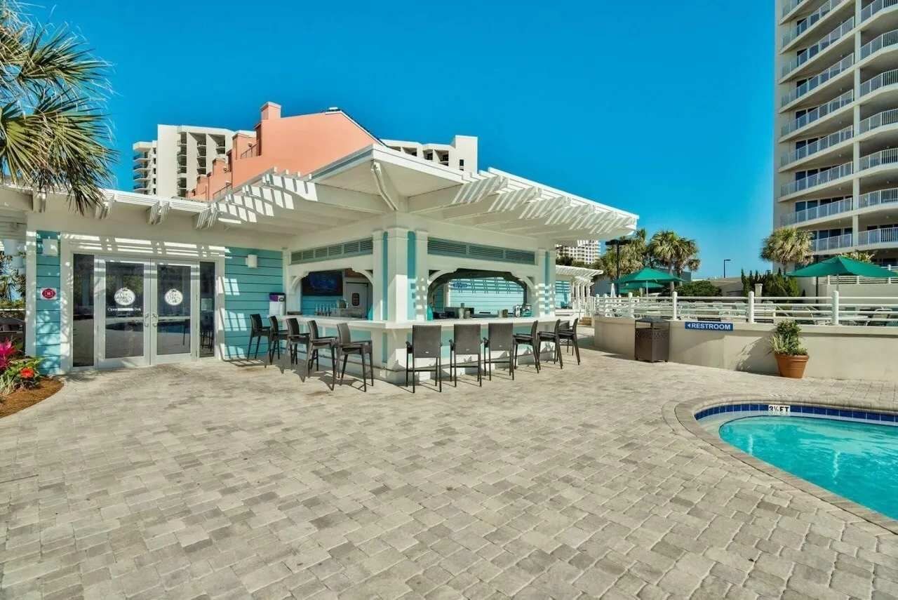 Uma área de bar à beira da piscina com assentos e piscina.