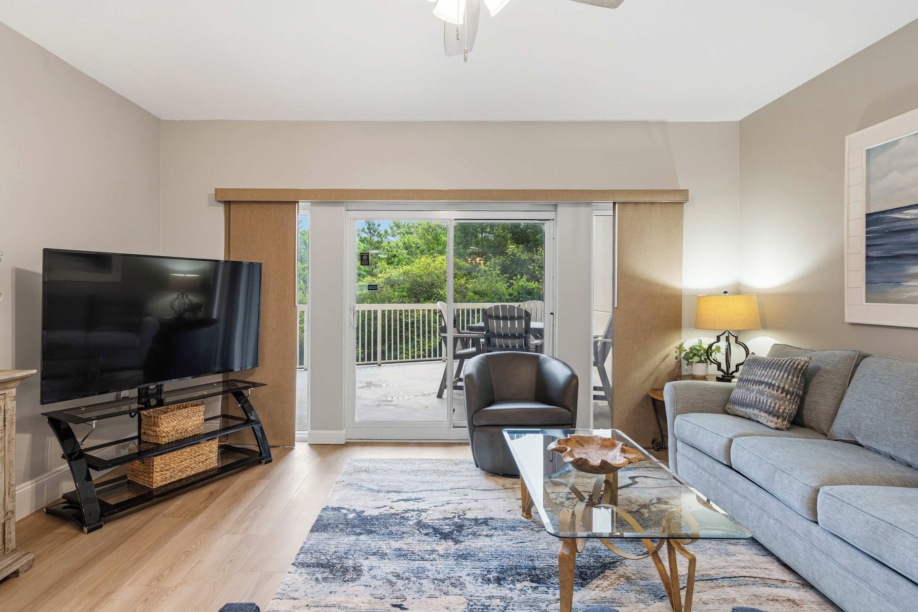 A living room with a television, sofa, coffee table, and a view to an outdoor balcony.