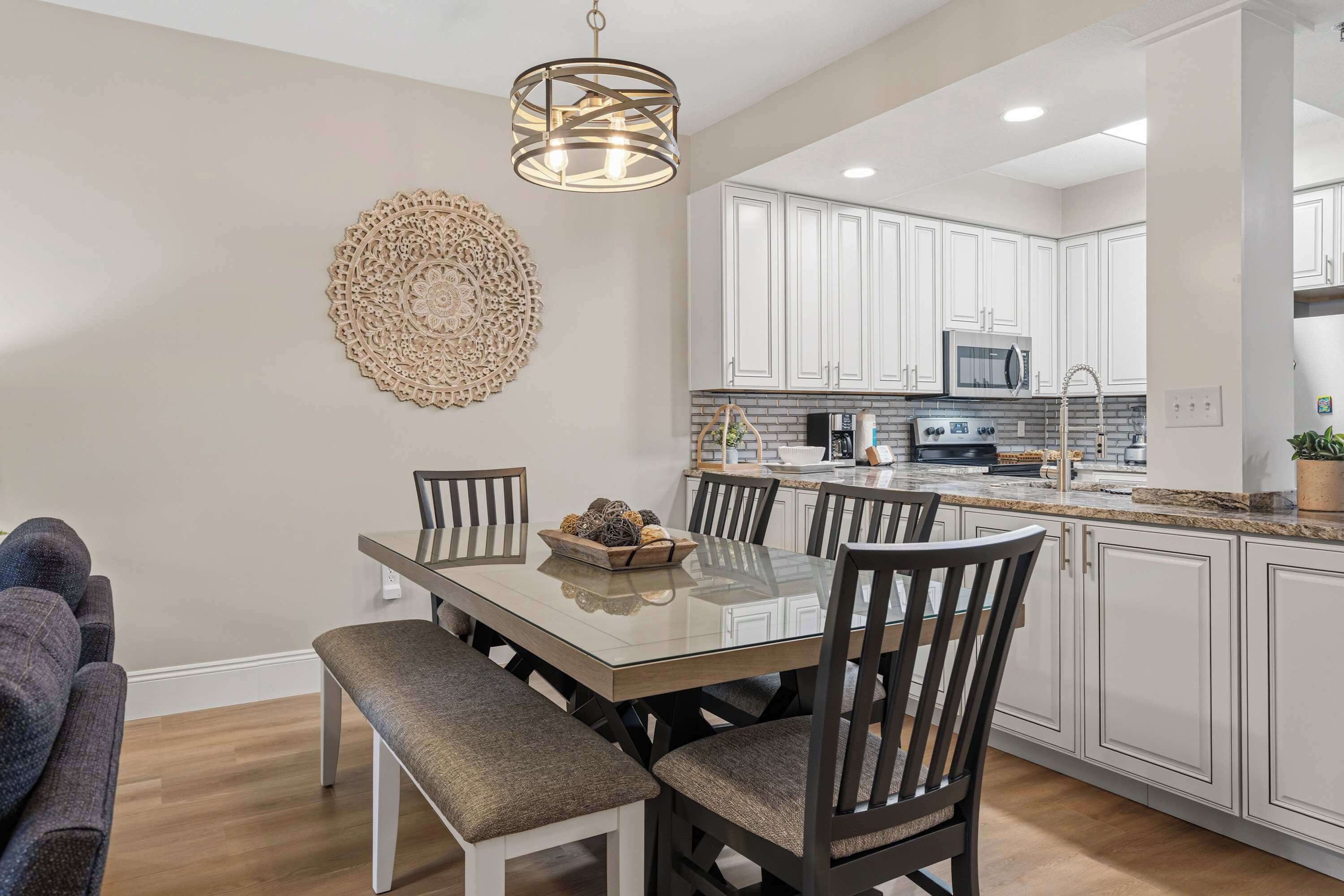 A modern kitchen with white cabinets, a stainless steel microwave, and a built-in oven.