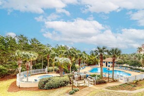Un resort con piscina, palmeras y un área de terraza amurallada.
