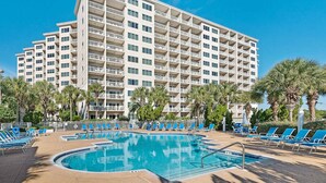 A hotel with a swimming pool surrounded by lounge chairs and palm trees. - 2BR condo with pool view & private balcony (Miramar Beach)
