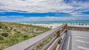 A beach view with a wooden boardwalk leading to the shore. - 2BR condo with pool view & private balcony (Miramar Beach)